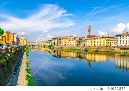 Ponte Vecchio bridge with colourful buildings houses over Arno River blue reflecting water 84022875