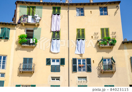 Wall of colorful buildings with shutter windows and drying bed linen on Piazza dell Anfiteatro square 84023115