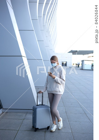 young woman with suitcase waiting for check-in at the entrance to the airport young woman with suitcase waiting for check-in at the entrance to the airport 84026844