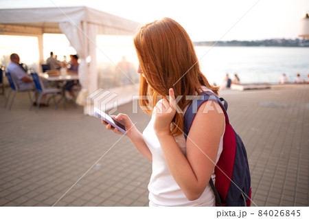 red-haired teen girl writes a message on the phone 84026845