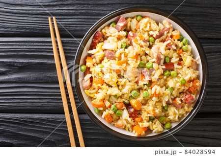 Yangzhou fried rice is a Chinese dish consisting of rice, egg and vegetables such as carrots, peas as well as shrimps, meat close up in the plate. Horizontal top view Yangzhou fried rice is a Chinese dish consisting of rice, egg and vegetables such as carrots, peas as well as shrimps, meat close up in the plate. Horizontal top view 84028594