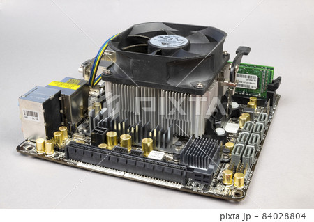 Computer motherboard with memory sticks and a cooler on a gray background. PC hardware Computer motherboard with memory sticks and a cooler on a gray background. PC hardware 84028804