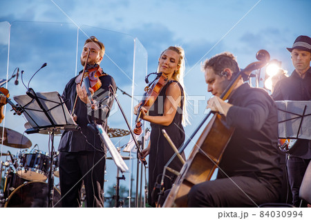 Musical ensemble performing orchestra concert against blue sky 84030994
