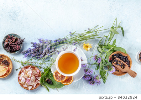 A cup of tea with dry fruit, flowers, and herbs, shot from the top A cup of tea with dry fruit, flowers, and herbs, shot from the top 84032924