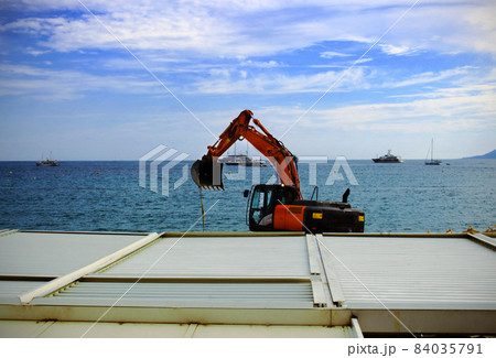 Excavator on metal roof top on sea water with yachts on the horizon 84035791