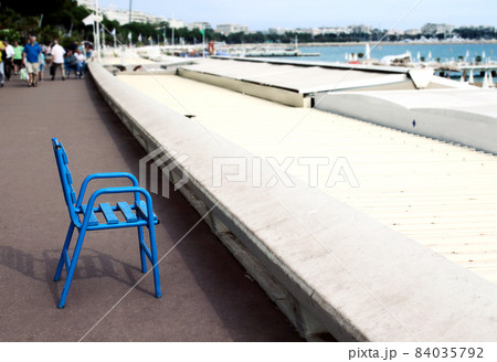 Blue chair on paved road seashore view on sea and sky with people 84035792