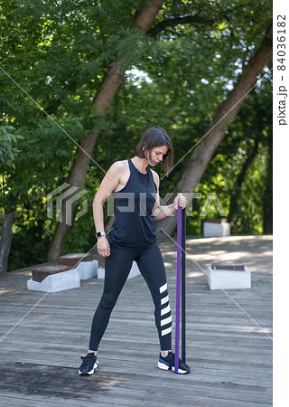 Fitness woman doing exercise for biceps with resistance band outdoors. Athletic girl workout. Fitness woman doing exercise for biceps with resistance band outdoors. Athletic girl workout. 84036182