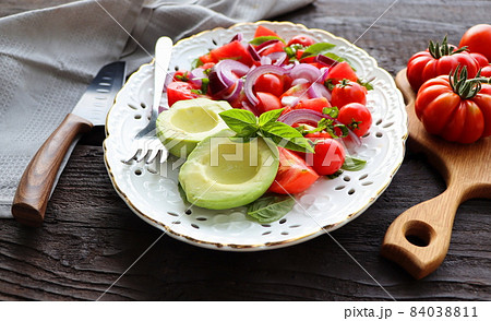 Fresh healthy avacado and tomato salad with onions on dark rusric background Fresh healthy avacado and tomato salad with onions on dark rusric background 84038811