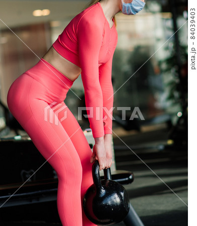 Coronavirus covid-19 prevention, fitness girl with a medical mask posing in gym. Fighting viruses. Coronavirus covid-19 prevention, fitness girl with a medical mask posing in gym. Fighting viruses. 84039403