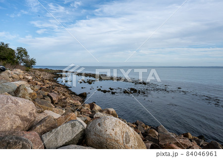 A rocky shoreline with blue water and a blu sky in the background. Picture from Skalderviken, Sweden A rocky shoreline with blue water and a blu sky in the background. Picture from Skalderviken, Sweden 84046961