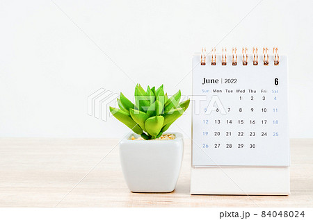 June 2022 desk calendar on wooden table. 84048024