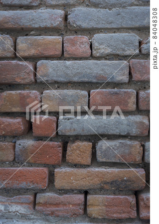 Red background of old vintage brick wall texture. Close-up view of an old stone brick wall with traces of blue paint. Vertical photography. Red background of old vintage brick wall texture. Close-up view of an old stone brick wall with traces of blue paint. Vertical photography. 84048308