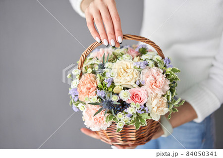 Flower arrangement in Wicker basket. Beautiful bouquet of mixed flowers in woman hand. Handsome fresh bouquet. Small flower shop and Flowers delivery. 84050341
