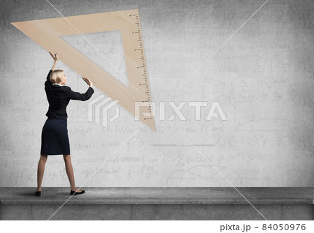 Woman in business suit holding big ruler Woman in business suit holding big ruler 84050976