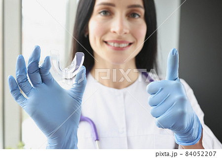 Stomatologist holding mouthguard for teeth and showing thumb up sign Stomatologist holding mouthguard for teeth and showing thumb up sign 84052207
