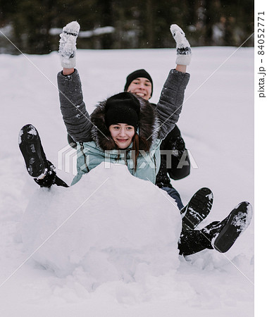 Couple of teenagers building snowman together in winter Couple of teenagers building snowman together in winter 84052771