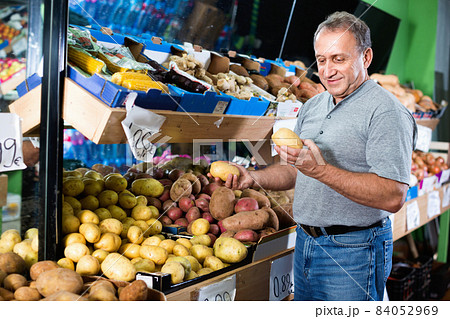 Smiling male is choosing potato in the supermarket. 84052969