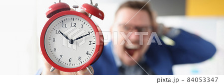 Screaming businessman holds red alarm clock in hands 84053347