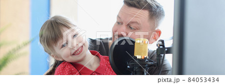 Dad and daughter engaged in music, there is microphone nearby 84053434