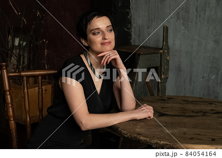 Attractive brunette woman with short haircut sits in thoughtful pose Attractive brunette woman with short haircut sits in thoughtful pose 84054164