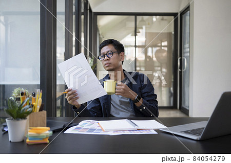 Young man graphic designer drinking coffee and working with color swatch in creative office. Young man graphic designer drinking coffee and working with color swatch in creative office. 84054279