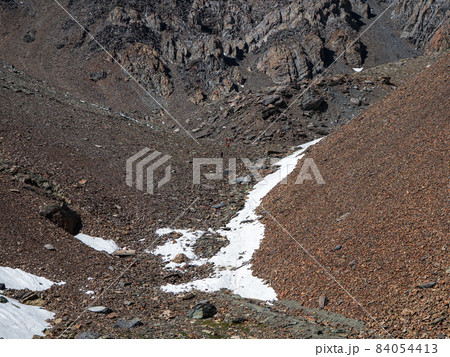 Minimalistic mountain landscape with glacier on rocky hill. Scant snow on pass. Beautiful summer view to highland nature. Mountain of stones on high altitude. 84054413