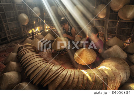 Two Vietnamese sisters craftsman making the traditional vietnam hat in the old traditional house in Ap Thoi Phuoc village, Hochiminh city, Vietnam, traditional artist concept 84056384