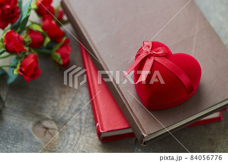 本の上に置かれたハート型のジュエリーケースとバラの花 84056776