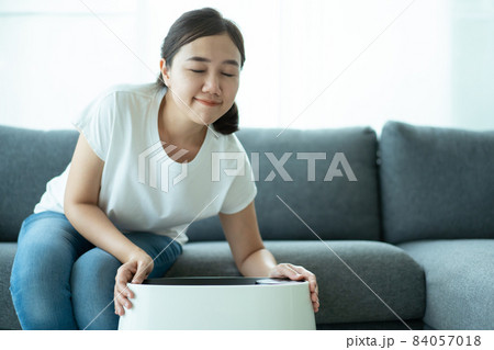 Woman using air purifier. Woman using air purifier. 84057018