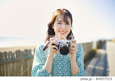 海辺でカメラを持って微笑む女性の写真素材 [84057523] - PIXTA