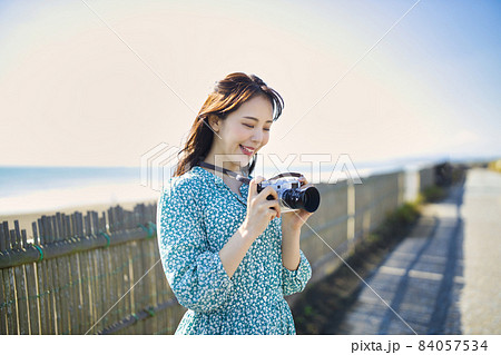 海辺で微笑む女性の写真 海辺でカメラを持って微笑む女性の写真素材 [84057534] - PIXTA
