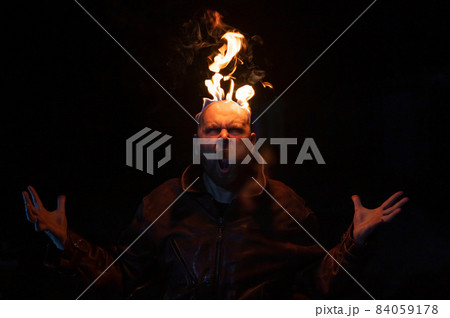 Bald man in a leather jacket with a burning head on a dark background. Bald man in a leather jacket with a burning head on a dark background. 84059178