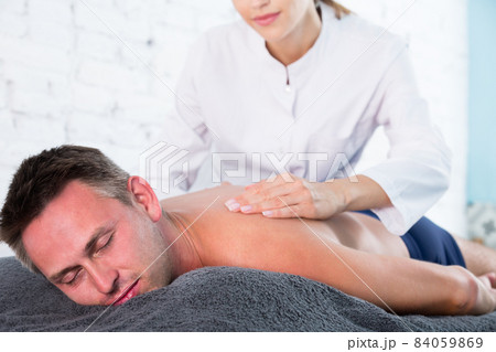 Female massage therapist massaging guy 84059869