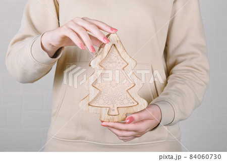 faceless woman with beige hoodie holding trendy Christmas wooden tree faceless woman with beige hoodie holding trendy Christmas wooden tree 84060730