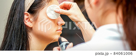 Makeup artist making professional makeup on the face of a young woman using an airbrush. 84061006