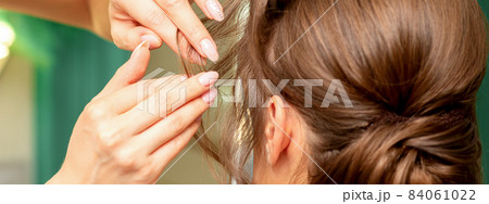 Close Up hairdresser stylist makes hairstyle for a young woman in a beauty salon. Close Up hairdresser stylist makes hairstyle for a young woman in a beauty salon. 84061022