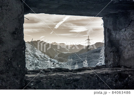 View of mountains and powerlines from the window of an abandoned stone fort  84063486