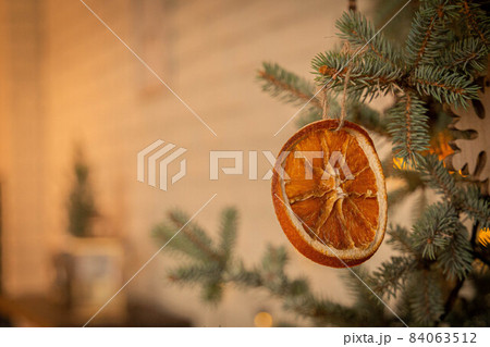 Dried orange slice hanging as decoration on a spruce branch 84063512
