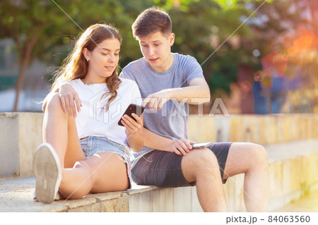 Teenagers with smartphones are siting on the step Teenagers with smartphones are siting on the step 84063560