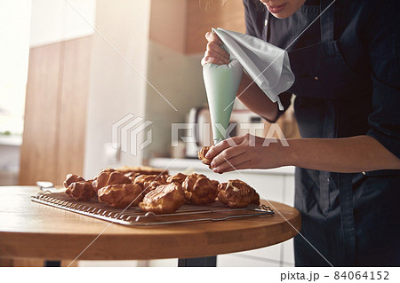 young professional female cook is preparing tasty cake at her light modern kitchen young professional female cook is preparing tasty cake at her light modern kitchen 84064152