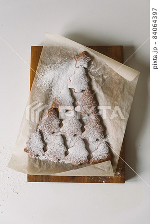 Gingerbread Christmas tree sprinkled with powdered sugar on parchment Gingerbread Christmas tree sprinkled with powdered sugar on parchment 84064397