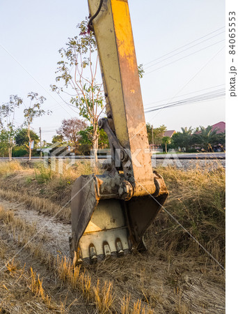 The large bucket with the sharp claw of the excavator is laying on the ground. The large bucket with the sharp claw of the excavator is laying on the ground. 84065553