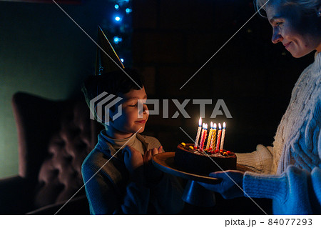 Happy child boy with closed eyes making wish before blowing candles on birthday celebration cake in dark room. Happy child boy with closed eyes making wish before blowing candles on birthday celebration cake in dark room. 84077293