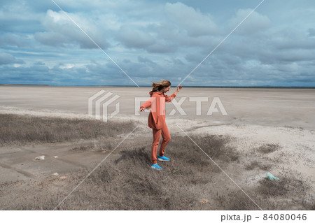 Ecological catastrophe in Israel, in the Middle East, the disappearance of the Dead Sea. shallowing, reduction. dried and, no greenery. A girl in an orange suit in a jump 84080046