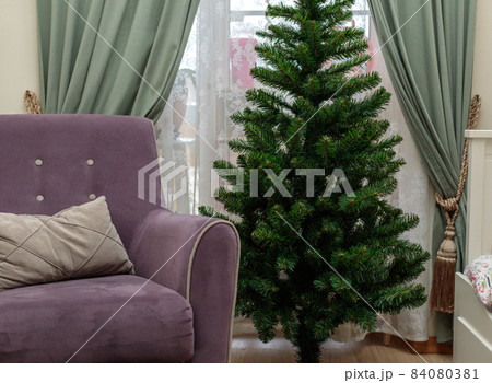 The interior of a room with an unadorned Christmas tree and an armchair. Preparing for the holiday The interior of a room with an unadorned Christmas tree and an armchair. Preparing for the holiday 84080381
