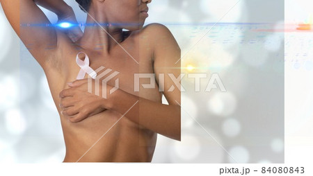 Mid section of woman wearing a pink ribbon on her chest against spots of lights on grey background 84080843