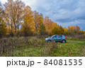 A blue passenger car on the background of grass and autumn forest. 84081535