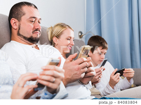 Parents and son using phones at home Parents and son using phones at home 84083804