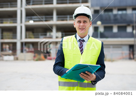 Architect standing on building site with documentation 84084001