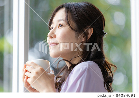 マグカップを持って窓辺に立つ女性 マグカップを持って窓辺に立つ女性 84084091